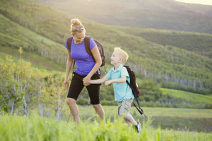 Family hiking in the mountains. A young mother and her son take a hike together in the mountains on a beautiful summer evening. Holding hands and enjoying their time together