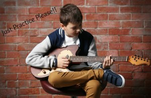 Cute little boy playing guitar on brick wall background