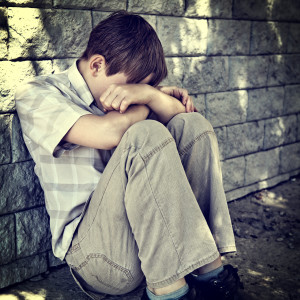 Toned Photo of Sad and Stressed Kid sit by the Wall outdoor