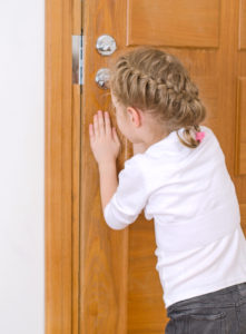 Cute little girl opening door to someone.